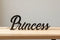 Black wooden decorative word 'Princess' on light wooden surface with neutral background for home decor