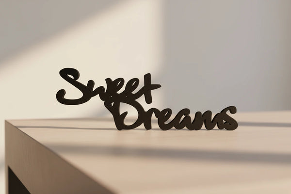 Black wooden 'Sweet Dreams' home decor sign on light wood surface with soft lighting